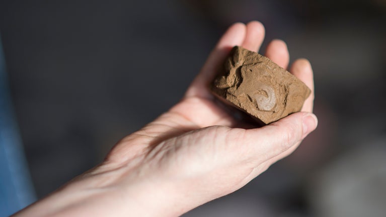 A circular clay chimney roulette with a rabbit pattern held in an outstretched hand